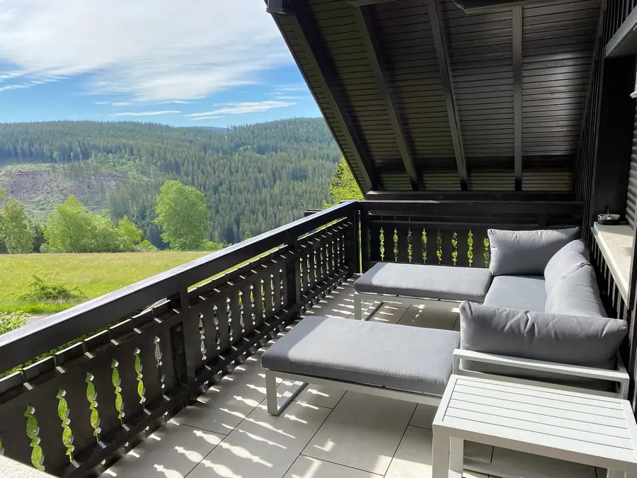 Balkon mit Loungemöbeln und Blick auf Wald und Wiesen