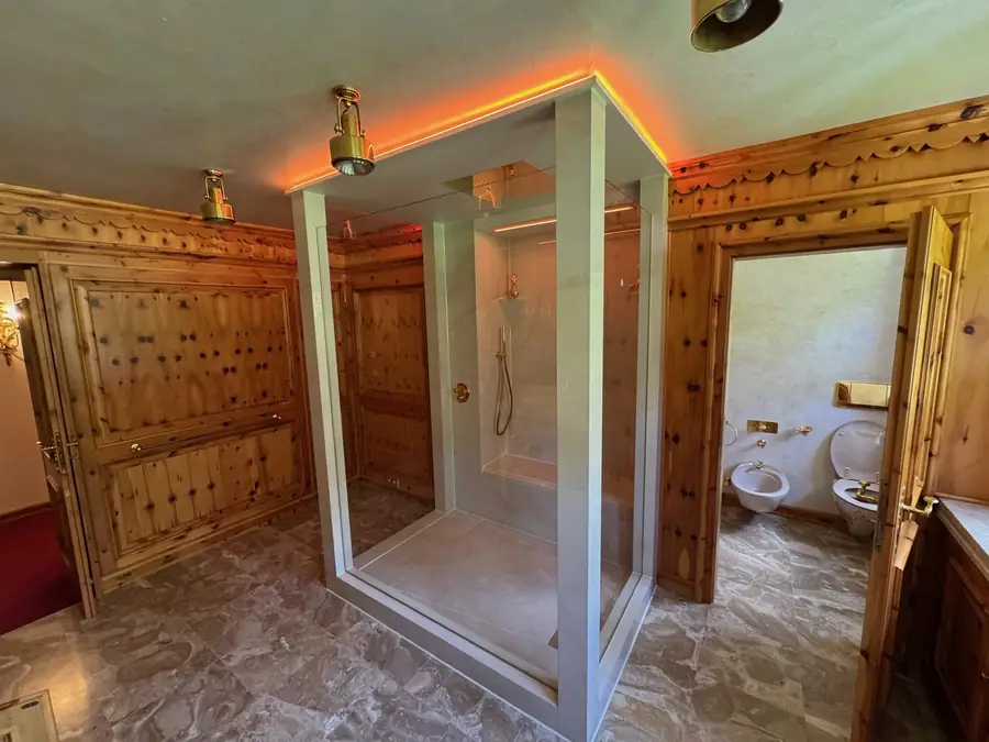Begehbare Glasdusche mit Regenbrause im holzvertäfelten Bad