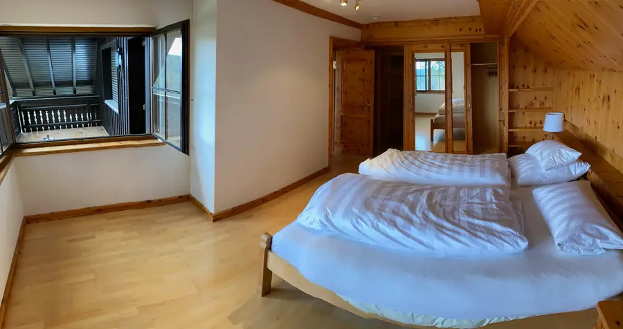Hauptschlafzimmer mit großem Doppelbett, Fenster zum Balkon und Spiegelschrank