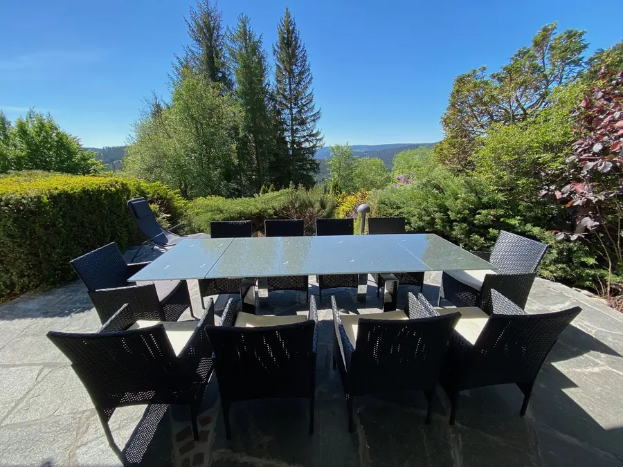 Terrasse mit langem Tisch, Hecke und Blick über die Bäume auf die Schwarzwaldhöhen